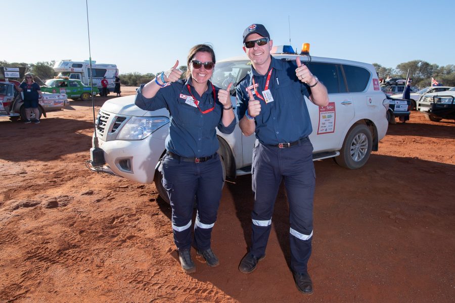 Two paramedics standing infront of a white 4WD with their thumbs up