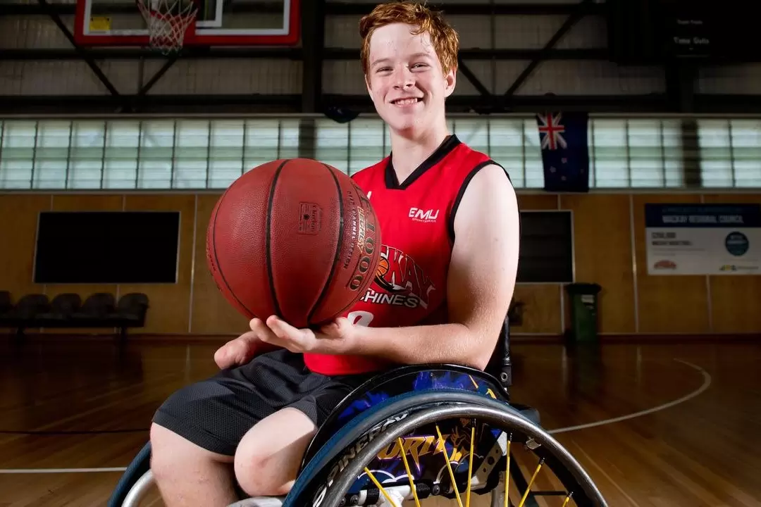 Grant recipient Brayden happy in his wheelchair playing basketball
