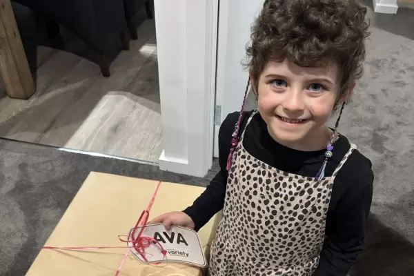 Happy grant recipient Ava receiving gift from Variety